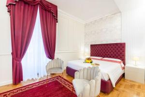 a bedroom with a bed with red curtains and two chairs at Domus Quirinale in Rome