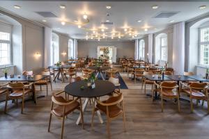 a dining room with tables and chairs and windows at Comwell Bygholm Park in Horsens