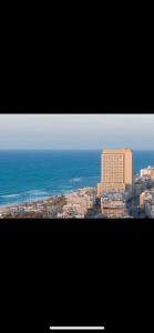 a view of a city with the ocean and a building at תמר על הים in Bat Yam