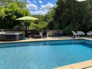 einen Pool mit Stühlen und einem Sonnenschirm in der Unterkunft Le jardin d'Eden in Valojoulx