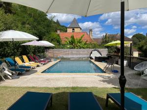a pool with chairs and umbrellas next to a house at Le jardin d'Eden in Valojoulx