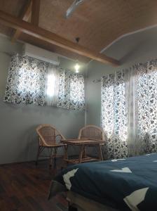 a bedroom with two chairs and a table and windows at SnowGoose Group of Houseboats in Srinagar