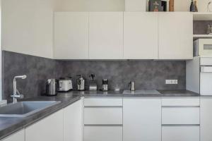 a kitchen with white cabinets and a sink at VoVoHouse in Ginduliai