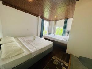 Duas camas num pequeno quarto com uma janela em Dolape Villa em Ella