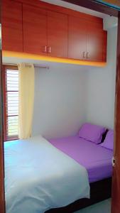 two beds in a small room with wooden cabinets at Kailash Guest Home in Mysore
