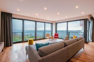 Homie Suites - Newly Built Seaside Apartments on Bakırköy Shore في إسطنبول: غرفة معيشة مع أريكة ونوافذ كبيرة