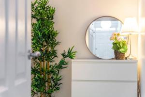 a mirror and a white dresser with a plant at 2-Bedroom Apartment in Greater London: Explore and Relax in Enfield