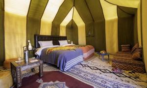 a bedroom with a bed and a couch in it at Four Season Camp in Merzouga