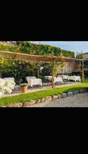 un giardino con tavoli e sedie e un pergolato di Hotel Casa Camilla a Verbania