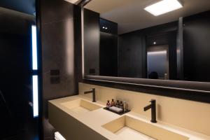 a bathroom with a sink and a large mirror at La Suite Matera Hotel & Spa in Matera