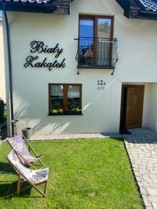 a chair sitting in the grass in front of a building at Biały Zakątek in Szklarska Poręba