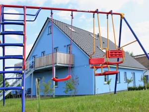 a playground with swings in front of a blue house at Holiday Home Blu Hus in Freest