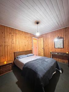 a bedroom with a large bed in a wooden wall at Chalé no mar de nuvens - Serra da bocaina in São José do Barreiro