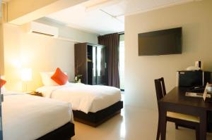 a hotel room with two beds and a desk and a television at Annex Lumpini Bangkok in Bangkok