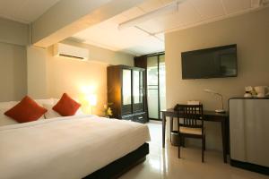 a bedroom with a bed and a desk and a television at Annex Lumpini Bangkok in Bangkok