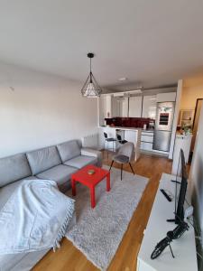 ein Wohnzimmer mit einem Sofa und einem roten Tisch in der Unterkunft Makovi Flat in Zenica