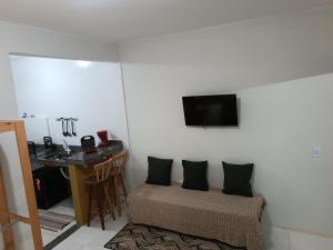 Habitación con cama, escritorio y TV en la pared. en Studio Mar & Sol en Armacao dos Buzios
