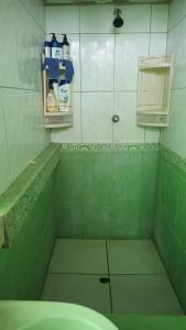 Baño de azulejos verdes con lavabo y estante en Casas Cueva, en Tumbes
