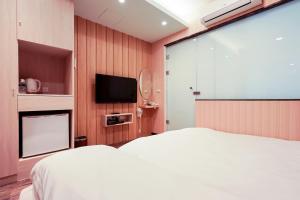 台南的住宿－久田豆旅宿 ，卧室配有白色的床和平面电视。