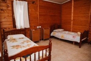 two beds in a room with wooden walls at Village of Peace - House 38 in Shkodër