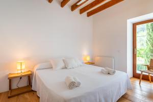 a white bedroom with a white bed with towels on it at Agroturismo Filicumis in Lloseta