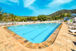 uma grande piscina com cadeiras e guarda-sóis em Hotel Fazenda M1 em Águas de Lindoia