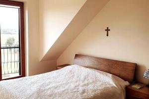 ein Schlafzimmer mit einem Bett mit einem Kreuz an der Wand in der Unterkunft Ducka Wola 10 - Cichy Zakątek, sielanka na wsi in Stromiec