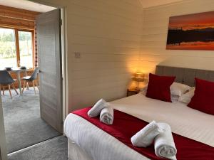 a bedroom with a bed with towels on it at Kinnaird Woodland Lodges in Pitlochry