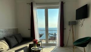 a living room with a couch and a view of the ocean at Almond Apartments in Sveti Stefan