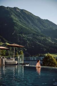 une femme dans une piscine avec une montagne dans l'établissement Alpina Alpendorf, à Sankt Johann im Pongau