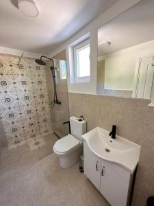 bagno con servizi igienici, lavandino e specchio di Almond Apartments a Sveti Stefan