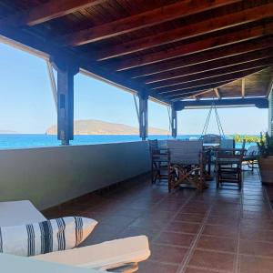 a patio with a table and chairs and the ocean at Tholos Alexandra's Beachfront House in Kavoúsion