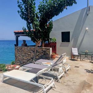 a group of chairs and a table and a tree at Tholos Alexandra's Beachfront House in Kavoúsion