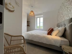 a white bedroom with a bed and a window at Le Loft de Babolène in Villefranche-de-Rouergue