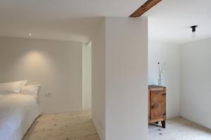a white bedroom with a bed and a wooden cabinet at BAR10ZIMMER in Dornbirn