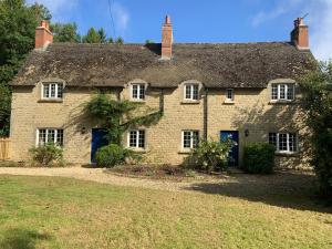 una antigua casa de piedra con puertas azules y un patio en Hornbeam Cottage en Kirtlington