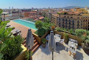 - Balcón con sombrillas y piscina en un edificio en The One Barcelona GL en Barcelona