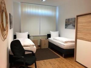 una stanza con due letti e una sedia di Motel de Winter - Motel - Apartmenthaus - Monteurzimmer a Castrop-Rauxel