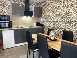 a kitchen with a wooden table and black chairs at Le P'tit Cocon in Calais