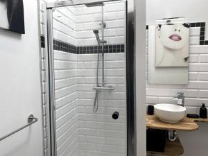 La salle de bains est pourvue d'une douche et d'un lavabo blanc. dans l'établissement Le P'tit Cocon, à Calais