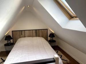 1 dormitorio con 1 cama blanca en el ático en Le P'tit Cocon, en Calais