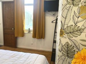 - une chambre avec un lit et un rideau avec des feuilles dans l'établissement Le P'tit Cocon, à Calais