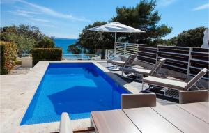 a swimming pool with two chairs and an umbrella at Villa Calla in Petrcane +35 photos