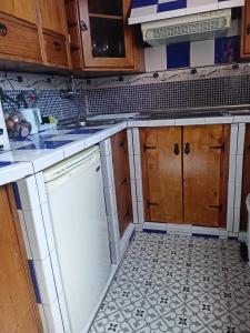 a kitchen with wooden cabinets and a white dishwasher at Servilux 3 in Torremolinos