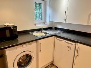 a kitchen with a sink and a washing machine at Pass the Keys Cosy one bed flat with parking and scenic views in Rickmansworth