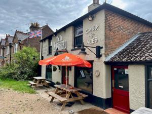 un edificio con dos mesas de picnic y una sombrilla en Pass the Keys Cosy one bed flat with parking and scenic views en Rickmansworth