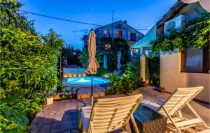 eine Terrasse mit 2 Stühlen, einem Sonnenschirm und einem Pool in der Unterkunft 1 Bedroom Awesome Apartment In Brodarica in Brodarica
