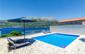 a swimming pool with an umbrella and a chair and a swimming pool at Villa Gabriela Korcula in Korčula