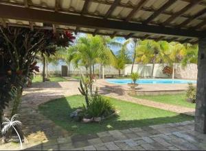 un patio trasero con piscina y palmeras en Casa LUXO Guaibim, en Guaibim