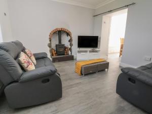 a living room with two couches and a tv at Ffriddoedd in Llanfairfechan